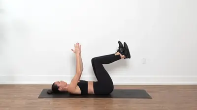 Woman lying on her back performing the Dead Bug exercise, extending one arm overhead and the opposite leg long