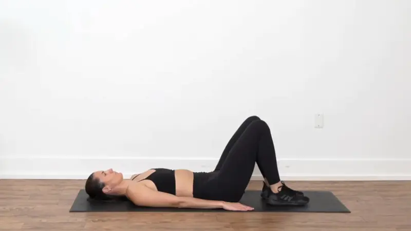 Woman lying on her back with one ankle crossed over the opposite knee in a figure four stretch for hip mobility.