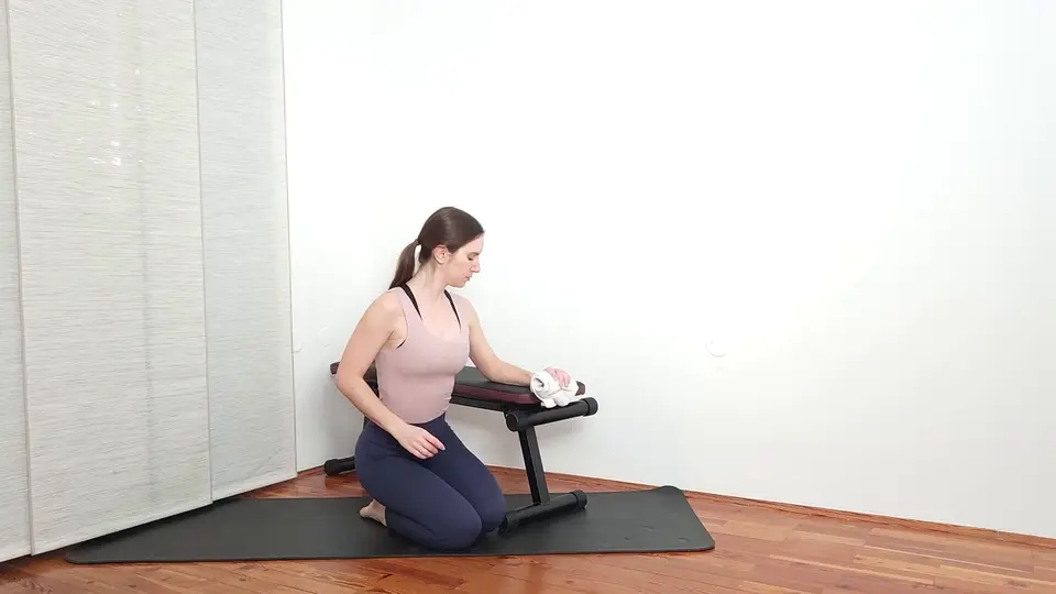 Towel crush grip exercise for tennis elbow, squeezing a rolled towel with the forearm resting on a bench