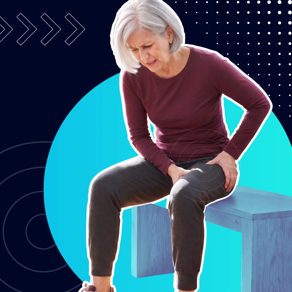 Woman in her sixties sitting on a bench, wincing and holding the front of her hip